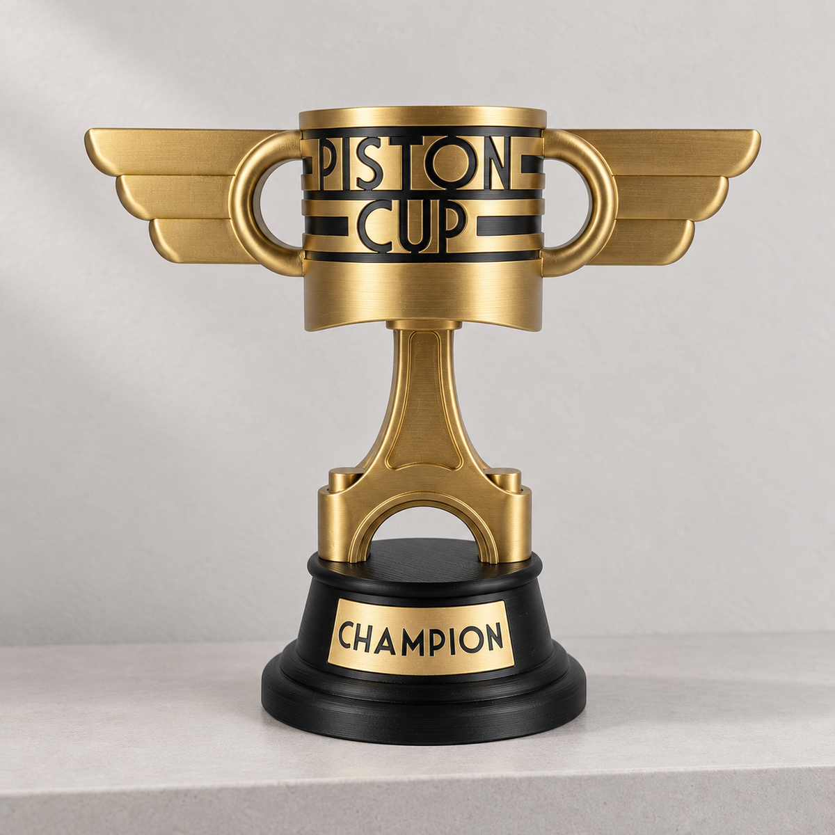 Altın renkli kanatlı Piston Kupası ve siyah Champion yazılı kaidesi.