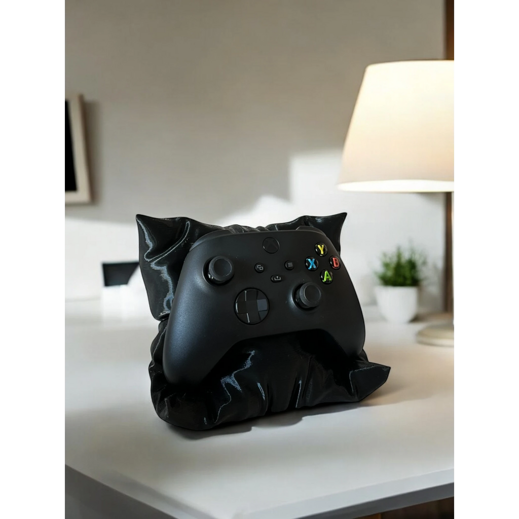 Black pillow-shaped stand holding an Xbox controller, ideal for gaming setups.