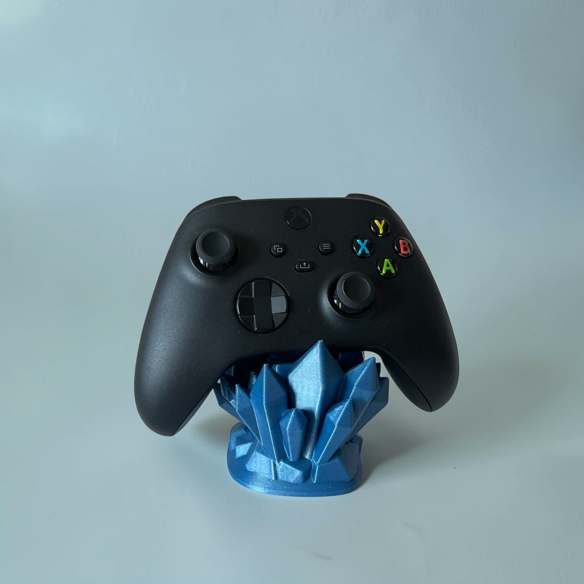 Magicland 3D blue crystal controller stand holding a black Xbox controller.