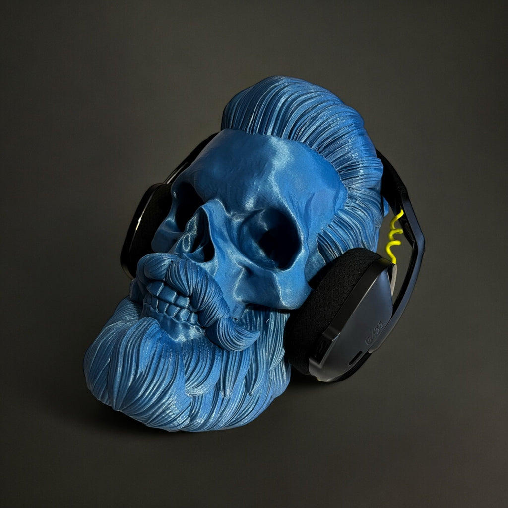 Blue 3D printed skull headphone stand with a beard and slicked-back hair, holding black headphones.
