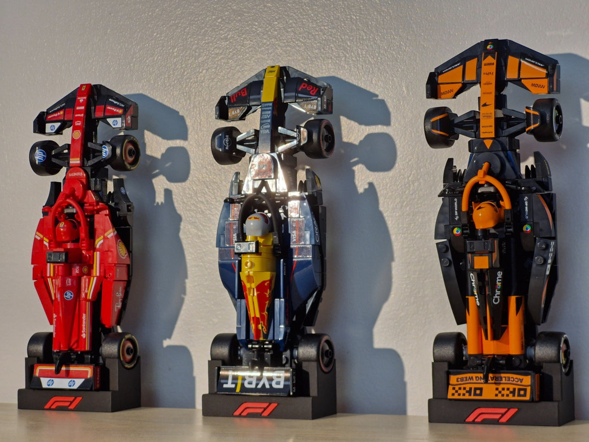 Magicland 3D F1 Lego Speed Champions dikey stantları, kırmızı, mavi ve turuncu renklerde üç adet model araba sergiliyor.