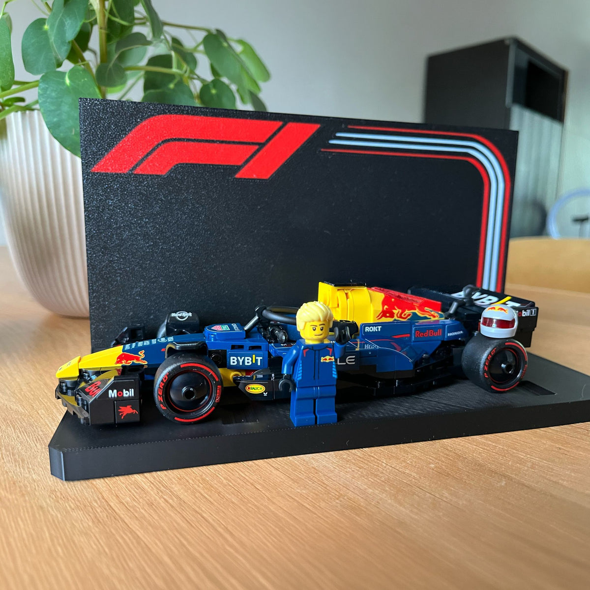 Magicland 3D F1 Lego Speed Champions teşhir standı, mavi ve sarı yarış arabası, figür ve F1 logosu.