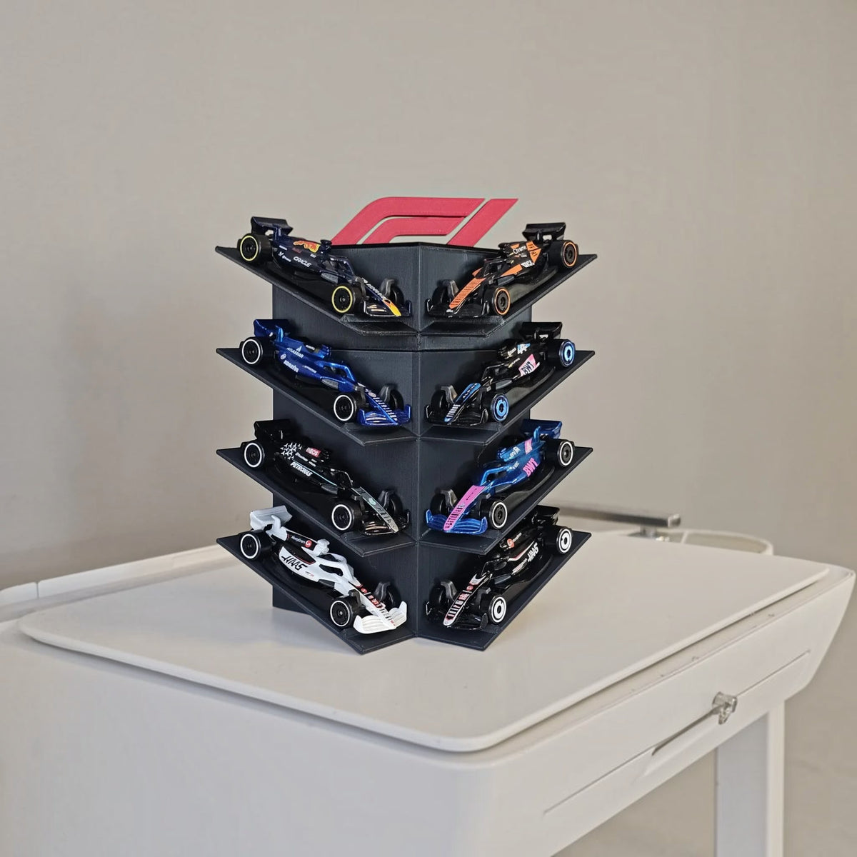 Magicland 3D 1:64 ölçekli F1 model araba sergileme standı, 8 araç kapasiteli siyah dikey kule ve kırmızı F1 logosu.