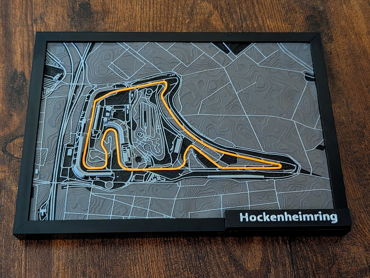 Magicland 3D F1 Hockenheimring pist haritası, 3D kabartmalı, turuncu pist çizgili, siyah çerçeveli.
