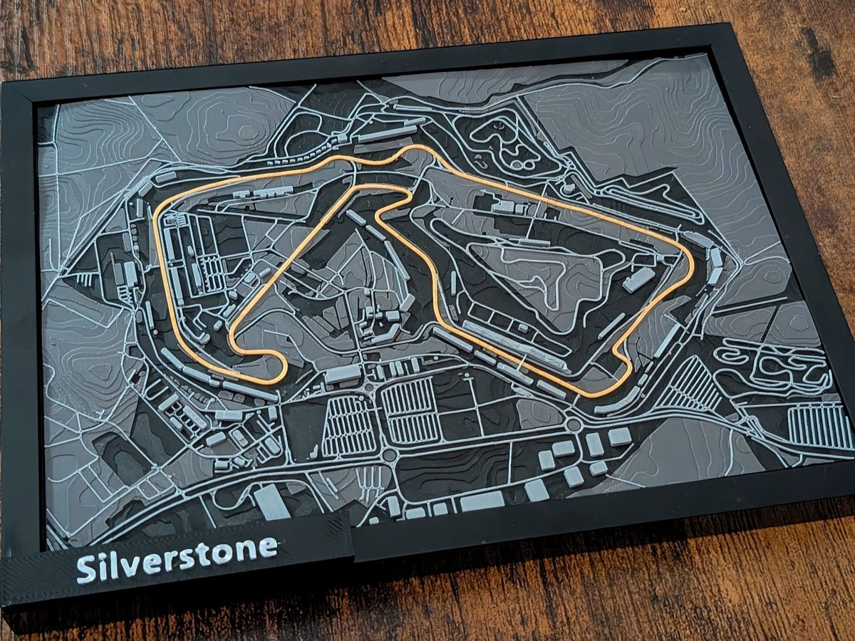 Magicland 3D Silverstone F1 pist 3 boyutlu kabartma haritası, turuncu yarış çizgisi ve gri topoğrafik detaylar.
