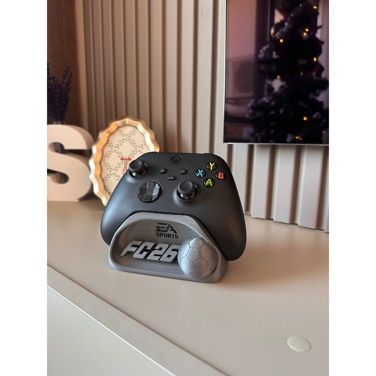 Magicland 3D FC26 Kol Tutucu Stant, Xbox oyun kumandası için tasarlanmış gri renkli bir stanttır. Üzerinde EA Sports logosu ve futbol topu detayı bulunur.