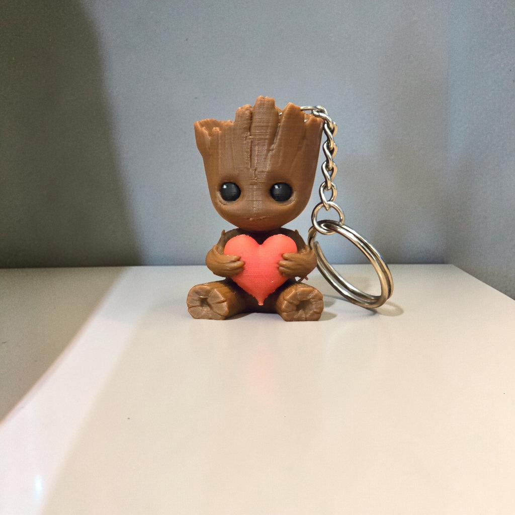 Magicland 3D Groot anahtarlık, kahverengi ve kırmızı renklerde, kalp tutan sevimli figür.