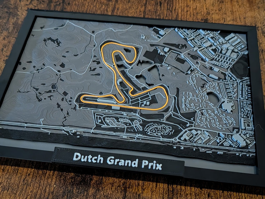 Magicland 3D, Hollanda Grand Prix pistinin kabartmalı 3 boyutlu haritası, turuncu renkte vurgulanmış pist ve gri tonlamalı arazi detayları.