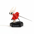 Magicland 3D Hollow Knight Figür - Hornet, kırmızı pelerinli, beyaz maskeli, kılıçlı ve küçük bir kuru kafa figürlü.