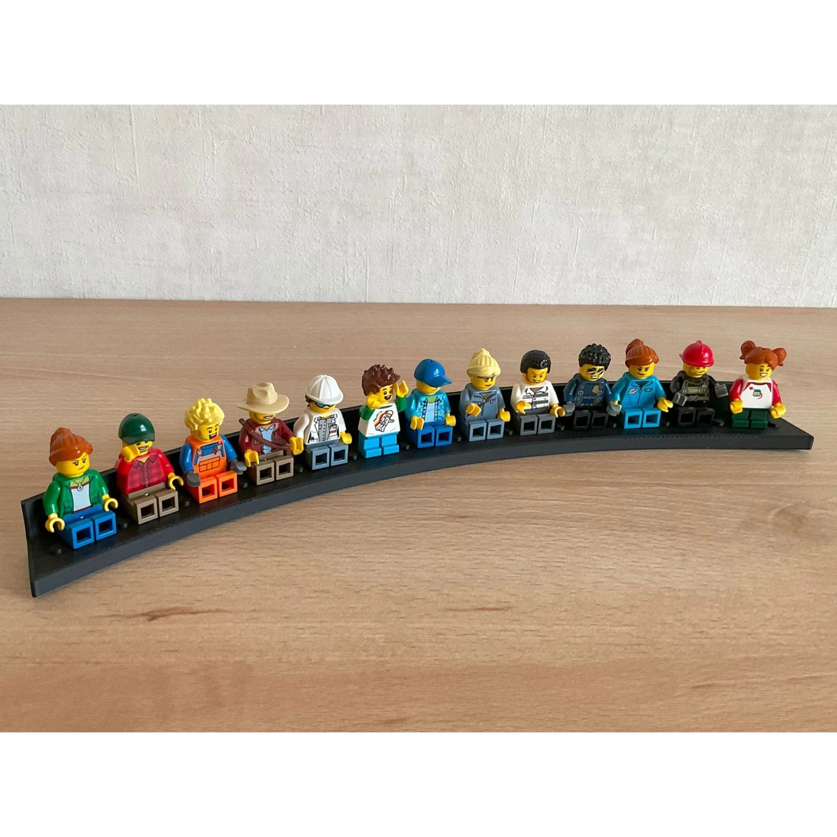Magicland 3D figür standı, 117 Lego figür kapasiteli, siyah, kavisli tasarım. Çeşitli Lego figürleri sergileniyor.