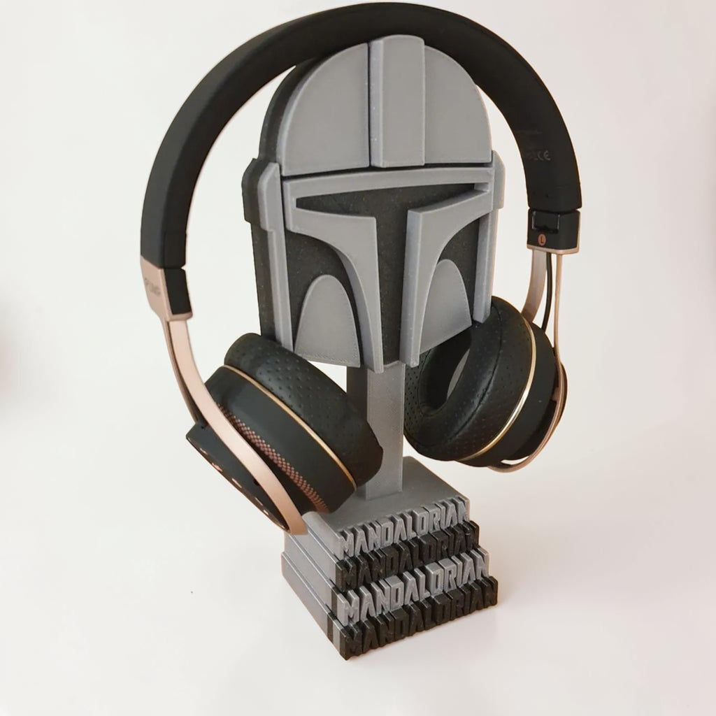 Magicland 3D Mandalorian helmet headphone stand in grey, holding black and rose gold headphones.