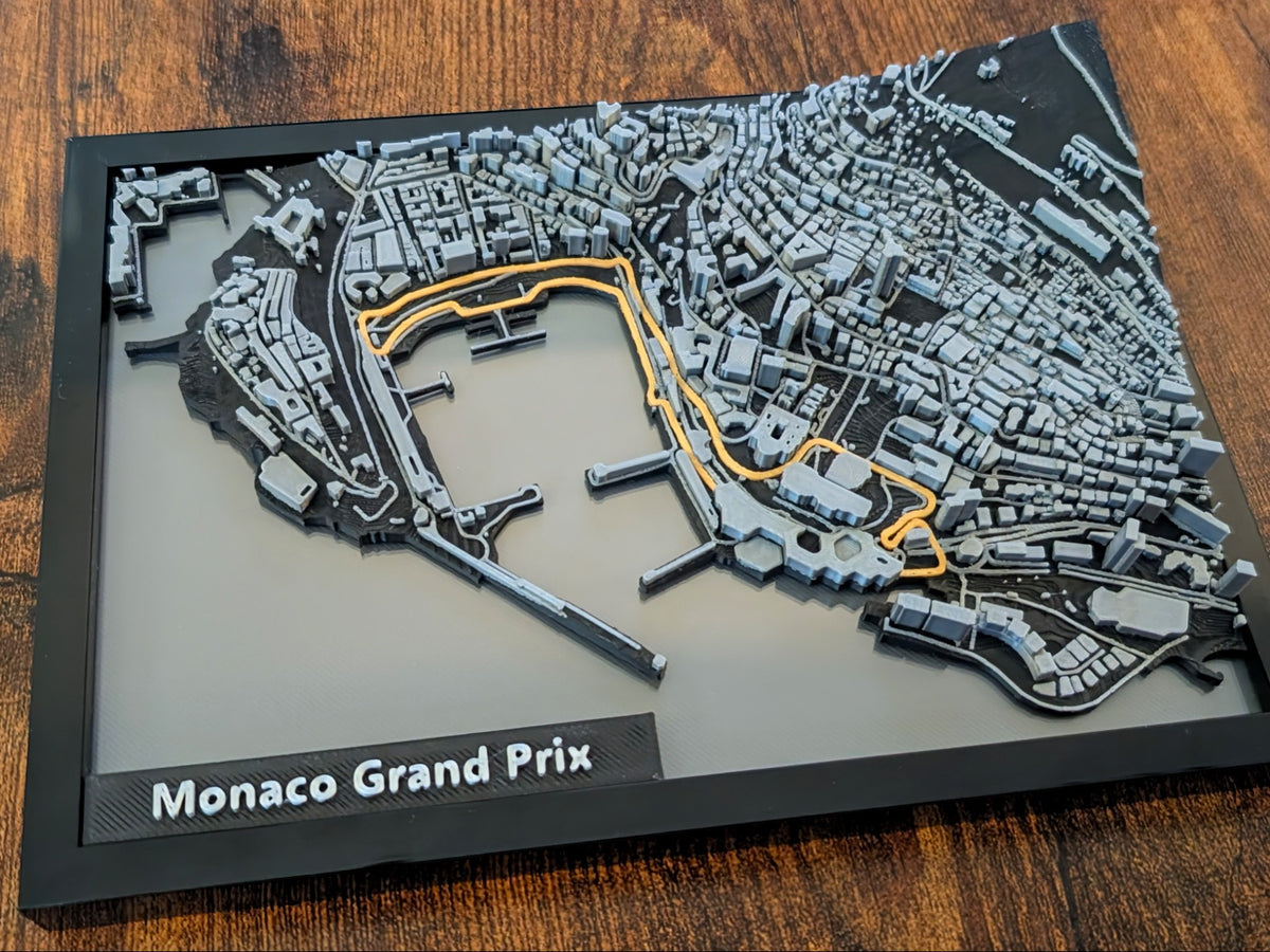 Magicland 3D Monaco Grand Prix 3D kabartma haritası, gri ve siyah binalar, turuncu yarış pisti detayı, siyah çerçeveli.