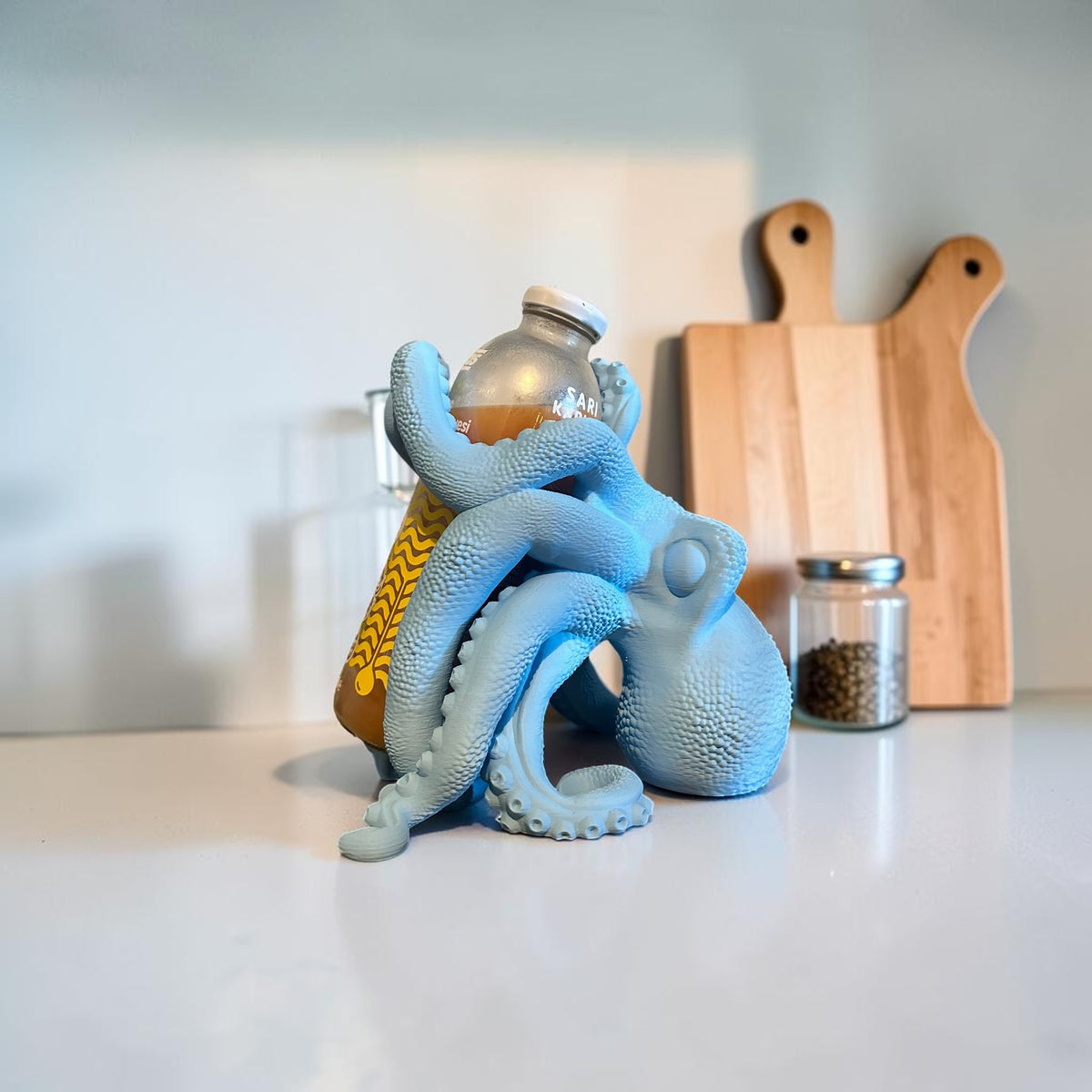 Magicland 3D light blue octopus wine bottle holder with tentacles wrapped around a bottle.