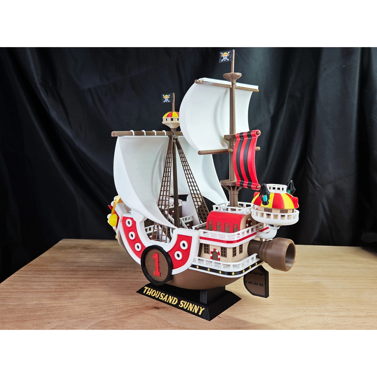 Magicland 3D'den One Piece Thousand Sunny gemi modeli. Beyaz yelkenleri, kırmızı ve sarı detayları, bayrakları ve kahverengi gövdesiyle.