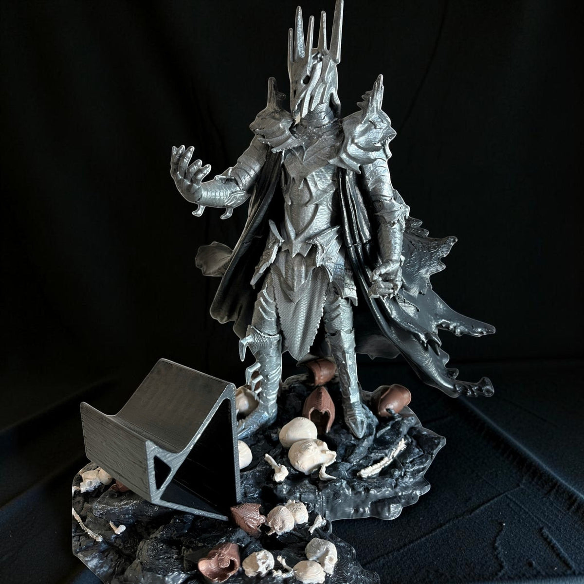 Magicland 3D Sauron figürlü kol tutacağı, zırhlı ve pelerinli figür, etrafında kuru kafa ve kemikler.