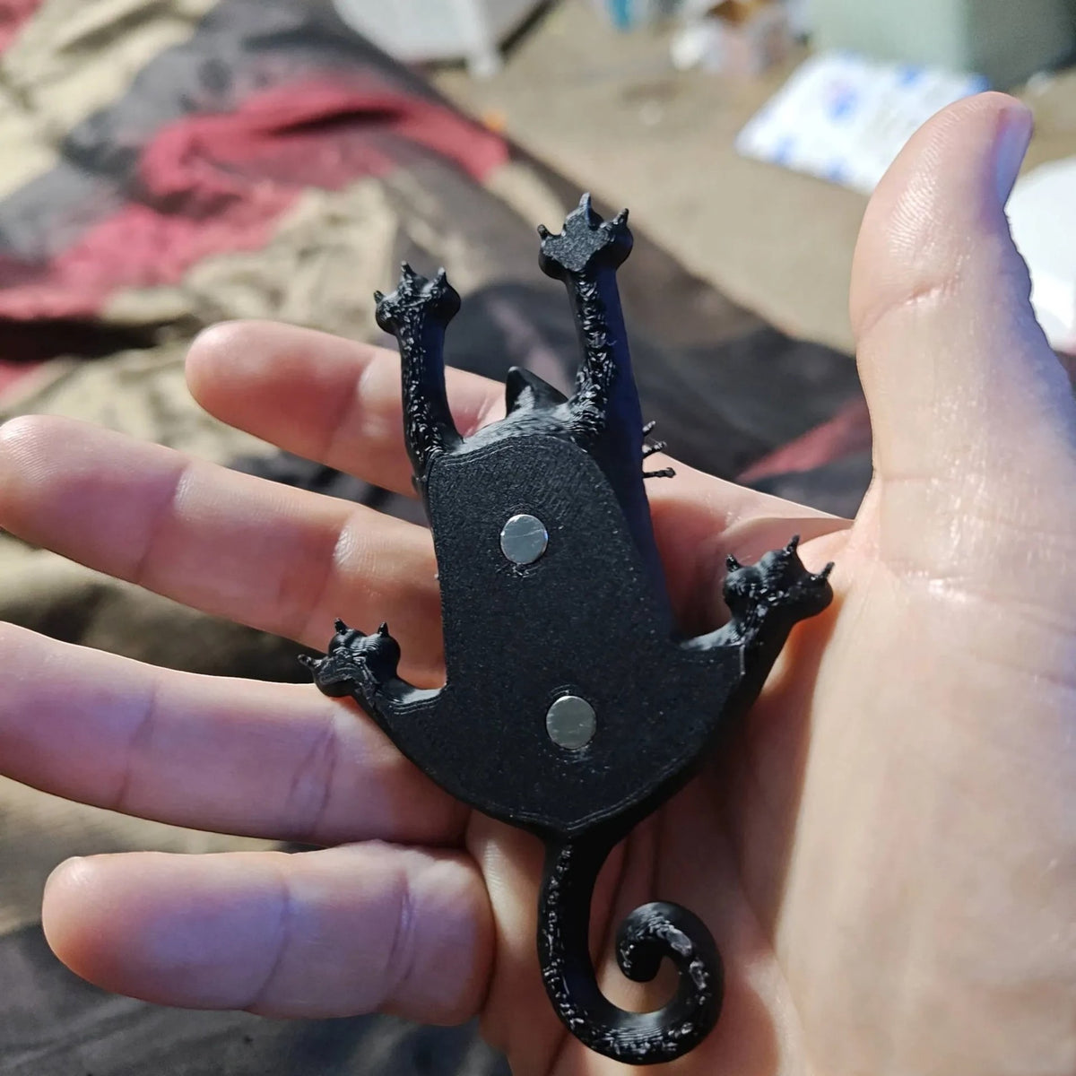 Magicland 3D tırmanan kedi figürlü siyah PLA buzdolabı magneti, arkasında iki adet gömülü mıknatıs ile avuç içinde.