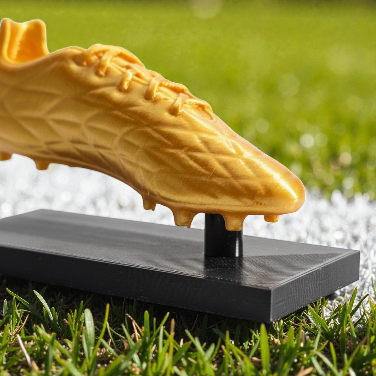 Magicland 3D altın rengi futbol ayakkabısı ödülü, siyah taban üzerinde duruyor. Futbol temalı ödül.