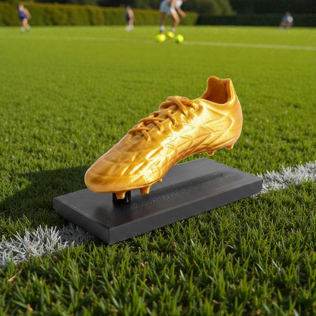 Magicland 3D altın futbol ayakkabısı ödülü, siyah bir taban üzerinde sergileniyor. Futbol temalı ödül.