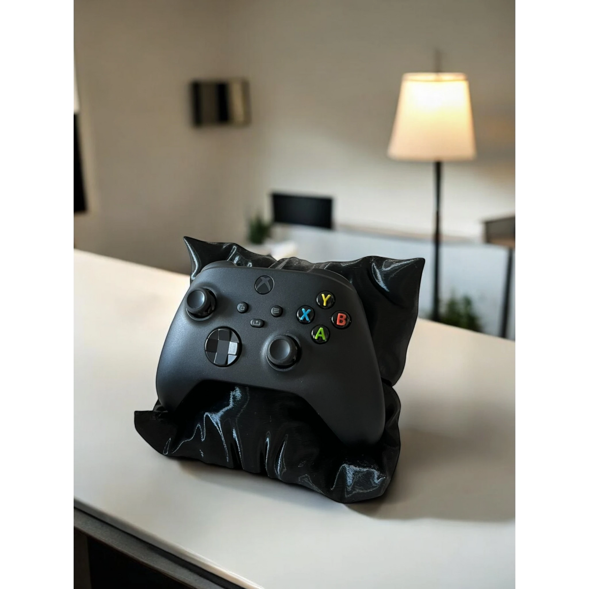 Black pillow-shaped stand holding a black Xbox controller. Magicland 3D.