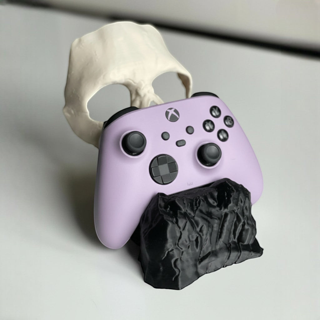 Magicland 3D Call of Duty Ghost controller stand, shaped like a skull and rock, holding a lavender Xbox controller.