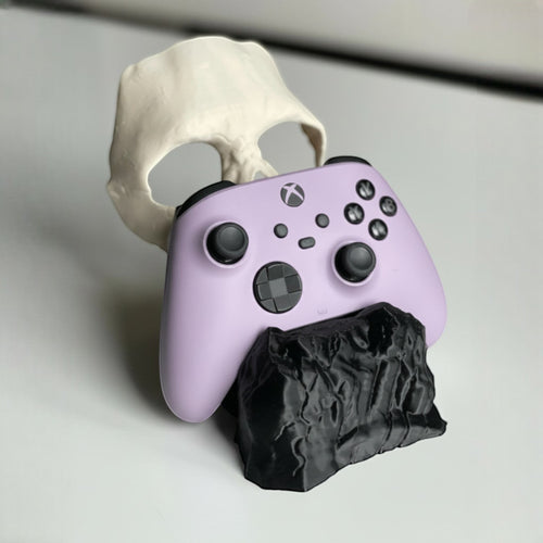 Magicland 3D Call of Duty Ghost controller stand, shaped like a skull and rock, holding a lavender Xbox controller.
