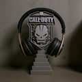Magicland 3D Call of Duty themed headset stand with skull emblem and tiered base. Black and gold headphones shown.
