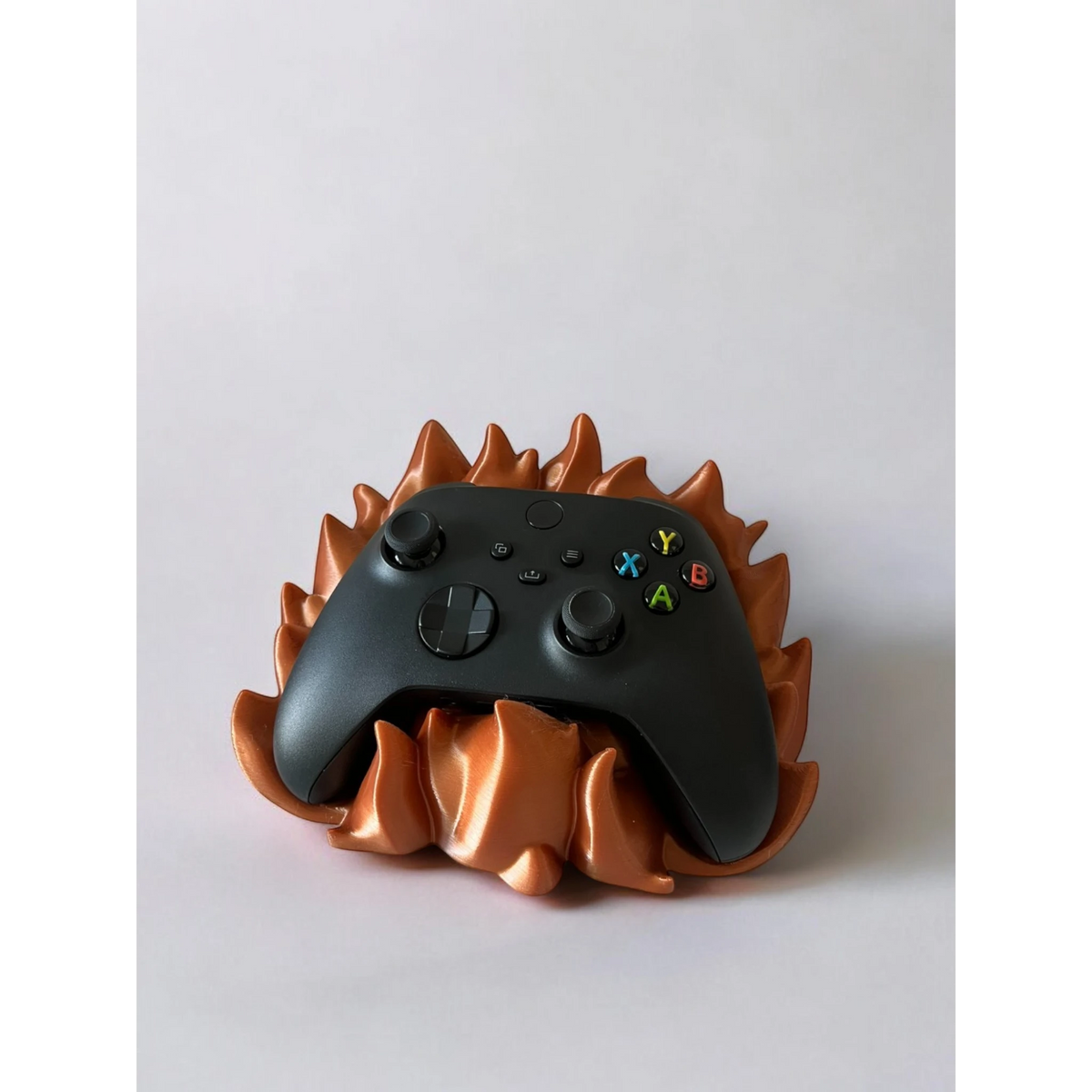 Magicland 3D flame-themed controller stand in copper, holding a black Xbox controller.