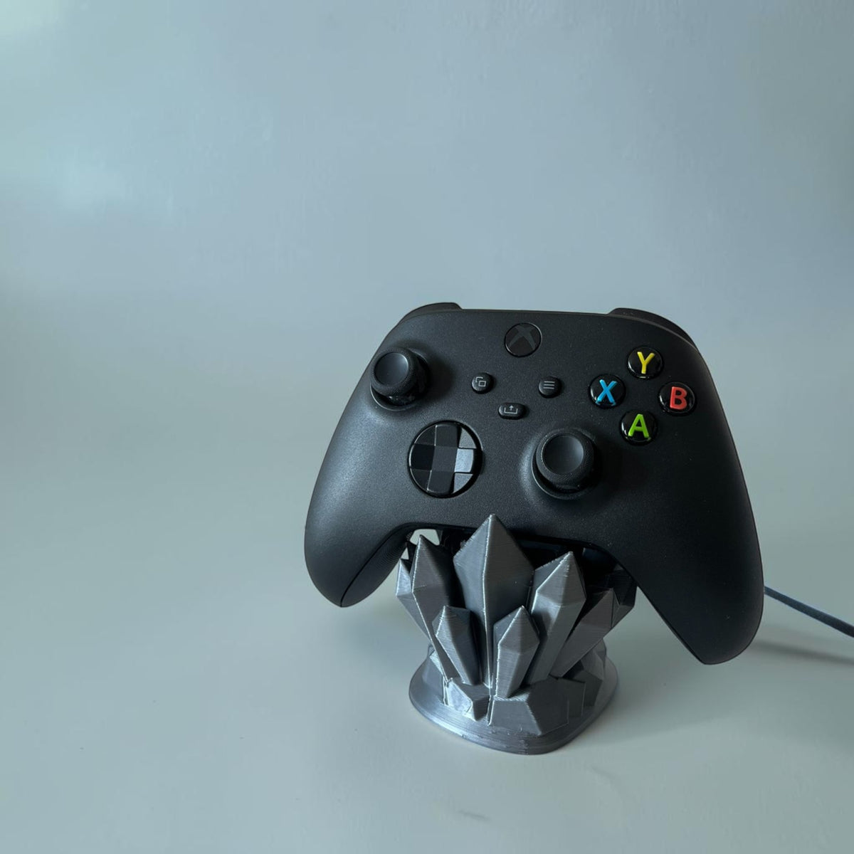 Magicland 3D crystal-shaped controller stand in grey, holding a black Xbox controller.