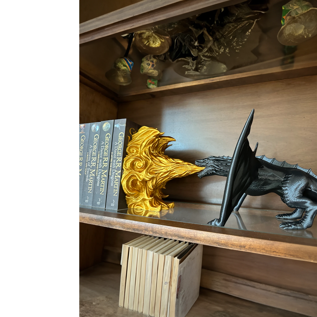 Magicland 3D black dragon breathing golden fire, decorative bookend set on a shelf with books.