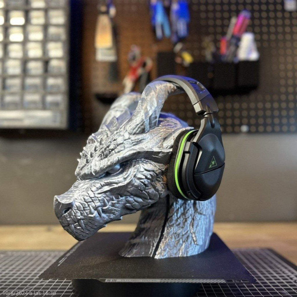 Magicland 3D silver dragon head headphone stand, detailed scales, holding black gaming headset with green accents.