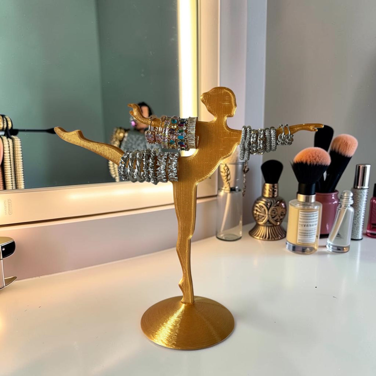 Gold-tone ballet dancer jewelry stand holding rings and bracelets. Decorative display for rings and earrings.
