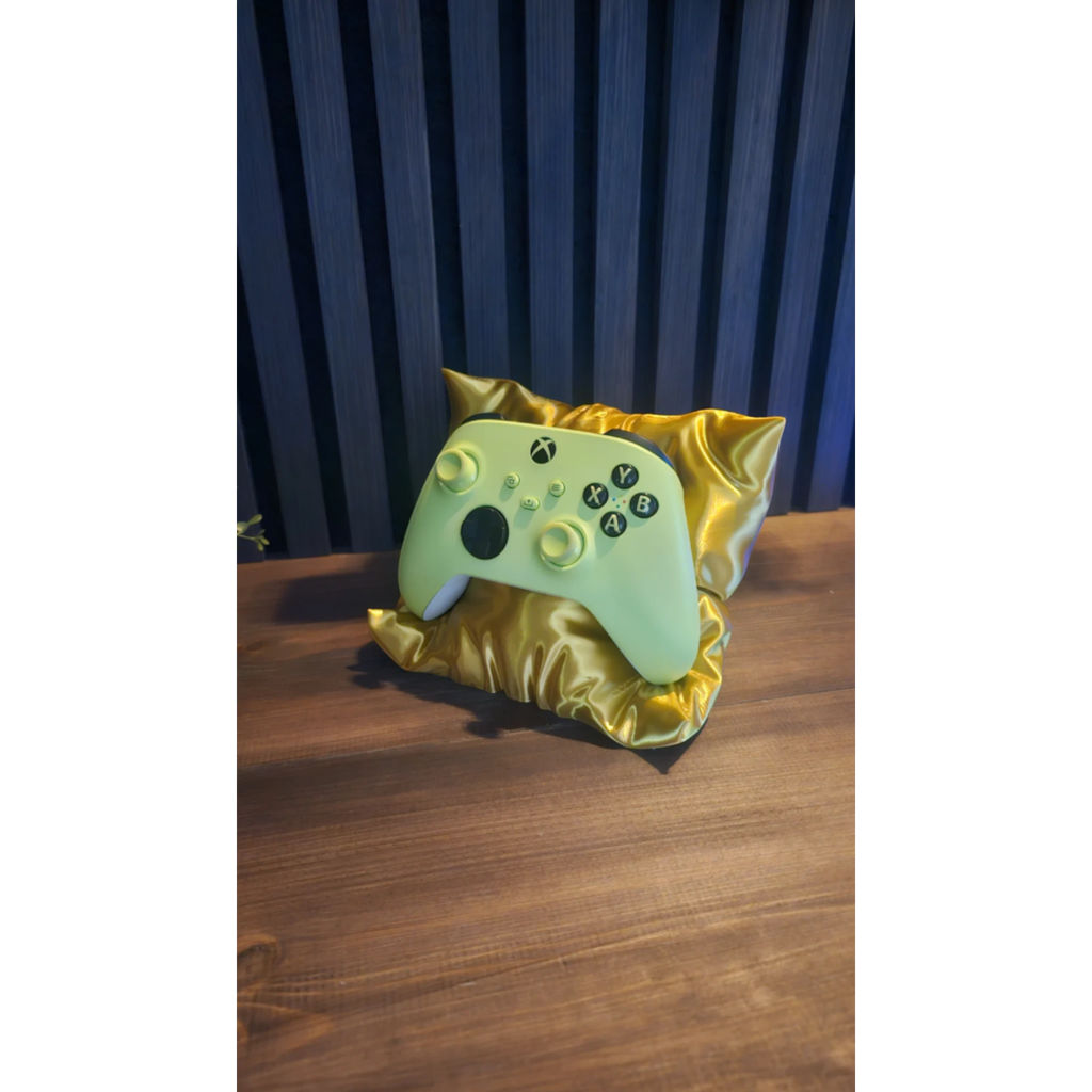 Magicland 3D decorative pillow stand in gold satin holding a light green Xbox controller.