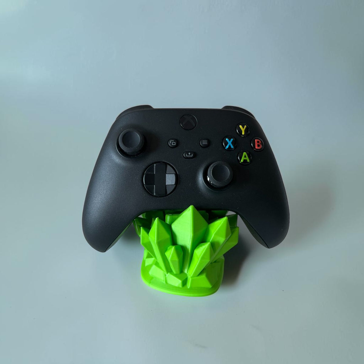 Magicland 3D green crystal controller stand holding a black Xbox controller. Decorative and functional.