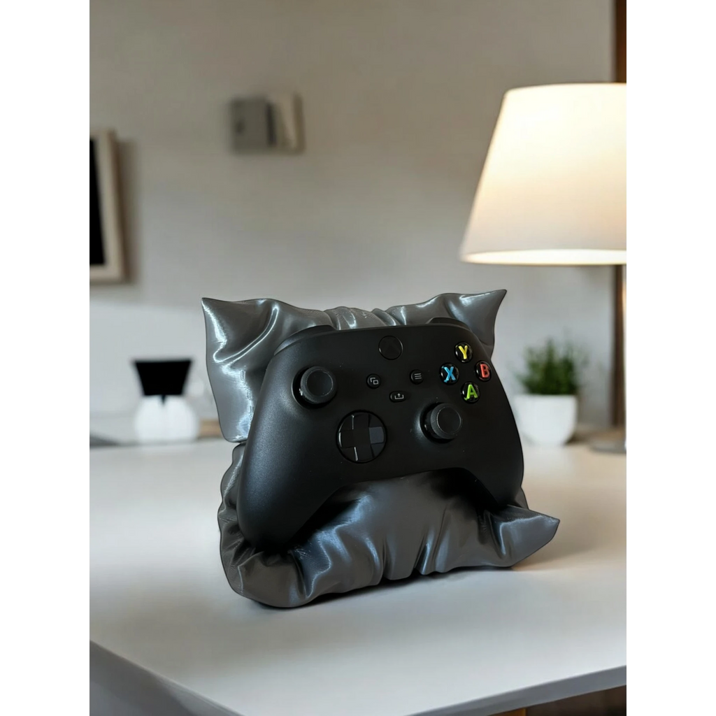 Magicland 3D grey pillow-shaped controller stand holding a black Xbox controller on a white desk.
