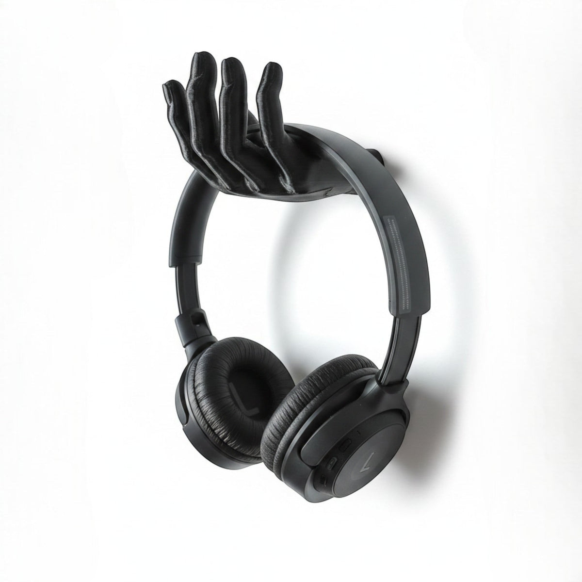 Black 3D printed hand-shaped headphone stand by Magicland 3D, mounted on a white wall.