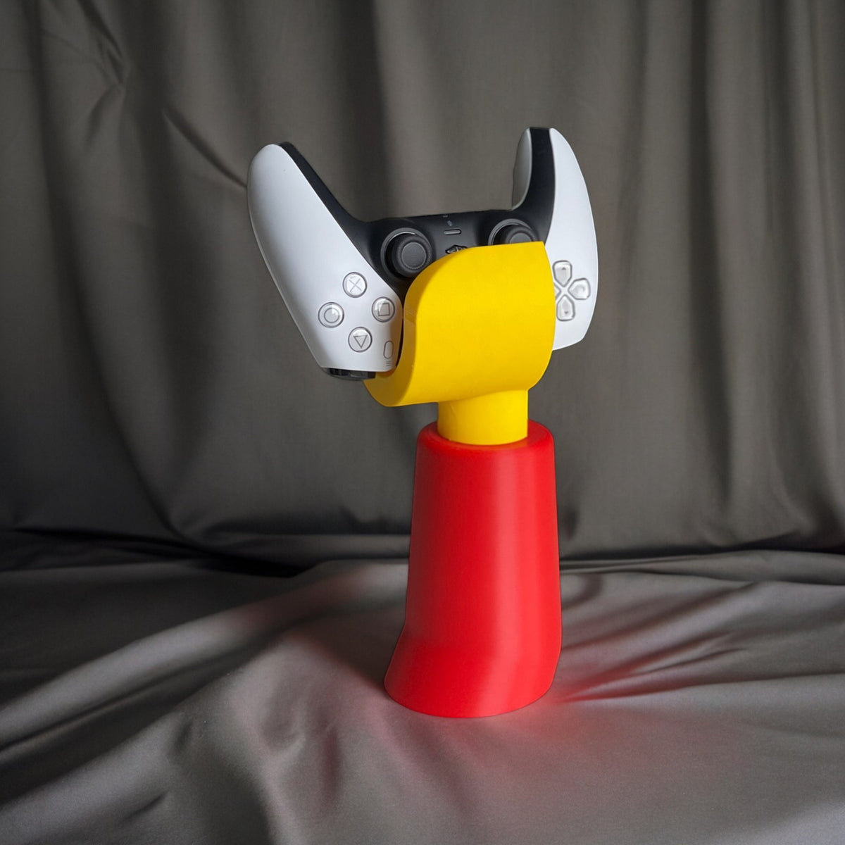 Magicland 3D Lego hand-shaped stand holding a white and black PS5 controller. Red base and yellow grip.