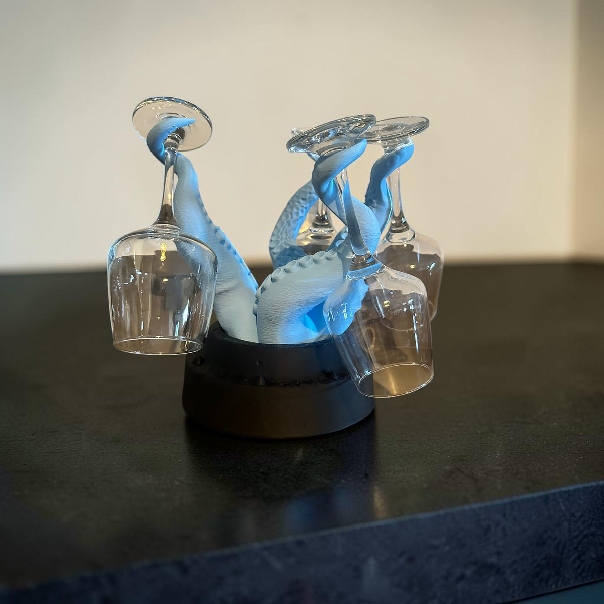 Magicland 3D octopus wine glass holder in light blue with black base, holding four clear wine glasses.