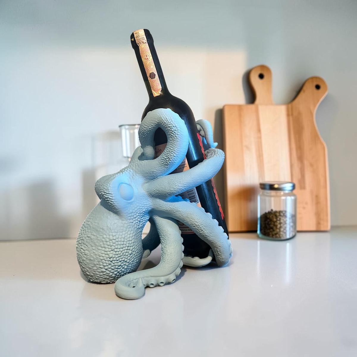 Light blue octopus wine bottle holder by Magicland 3D, with tentacles wrapped around a dark bottle.