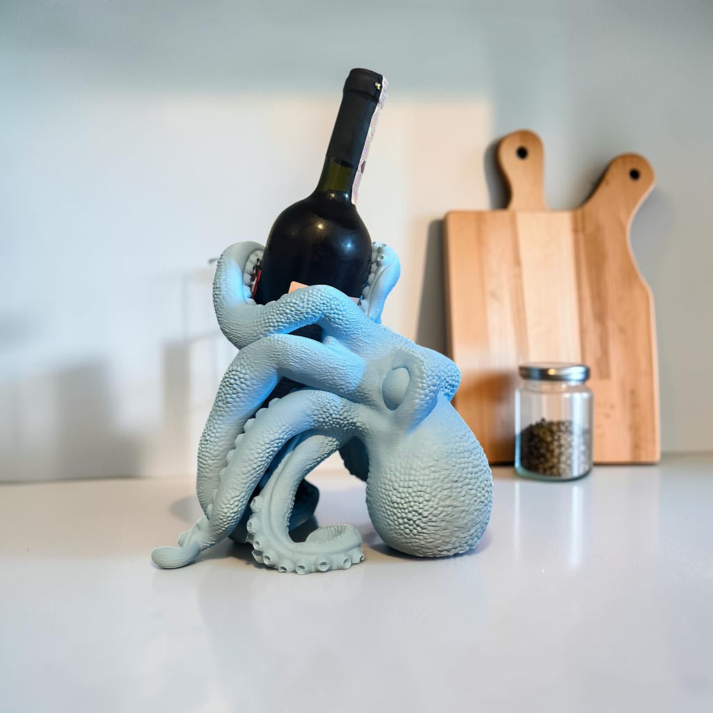 Magicland 3D light blue octopus wine bottle holder with tentacles wrapped around a dark bottle.