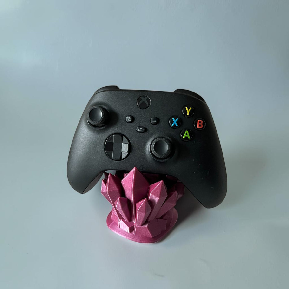 Magicland 3D pink crystal controller stand holding a black Xbox controller. Decorative gaming accessory.