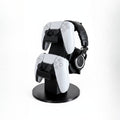 Magicland 3D black stand for two white PS5 controllers and headphones, keeping gaming setup tidy.