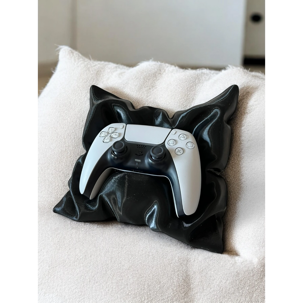 Magicland 3D black pillow-shaped stand holding a white PS5 controller on a textured cream cushion.