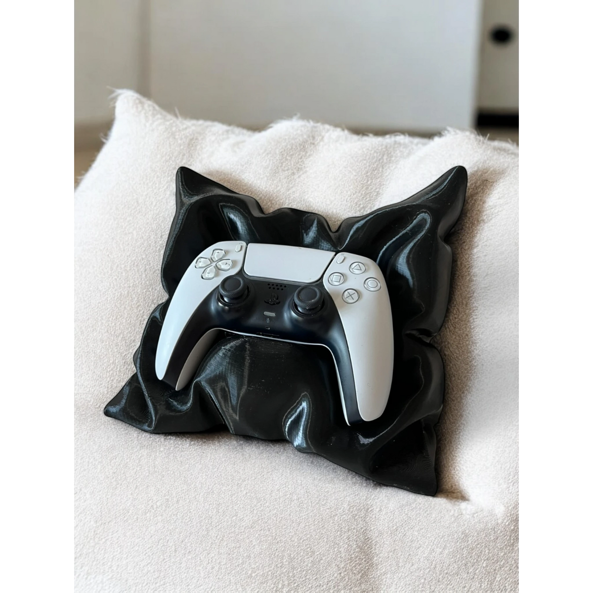 Magicland 3D black pillow-shaped stand holding a white PS5 controller on a textured cream cushion.