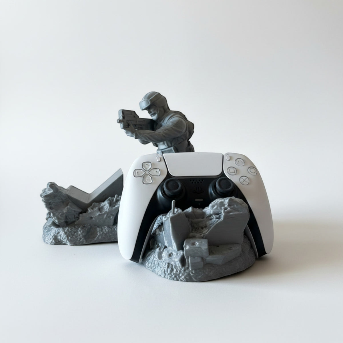 Magicland 3D Asker Figürlü Kol Standı, a grey soldier figure holding a gun, displays a white PS5 controller on a ruined base.