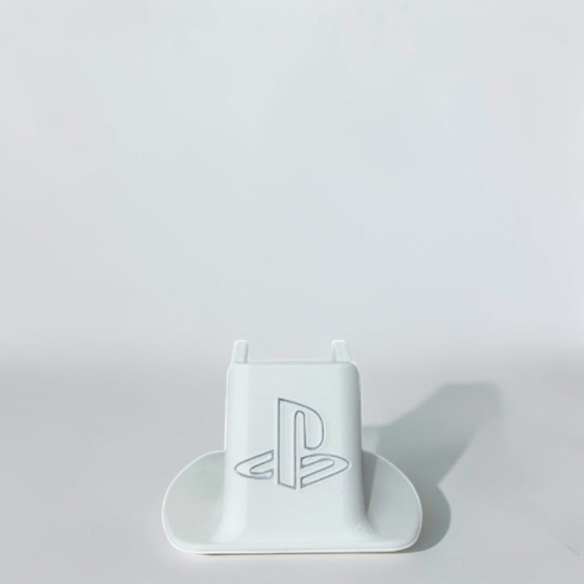 Magicland 3D white PS5 controller stand with embossed PlayStation logo, ideal for organizing gaming setups.