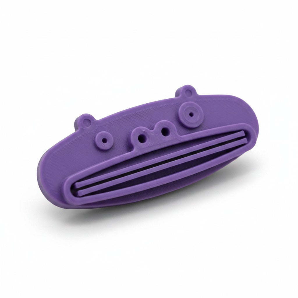 Magicland 3D purple pig-shaped toothpaste squeezer with slots for dispensing toothpaste.