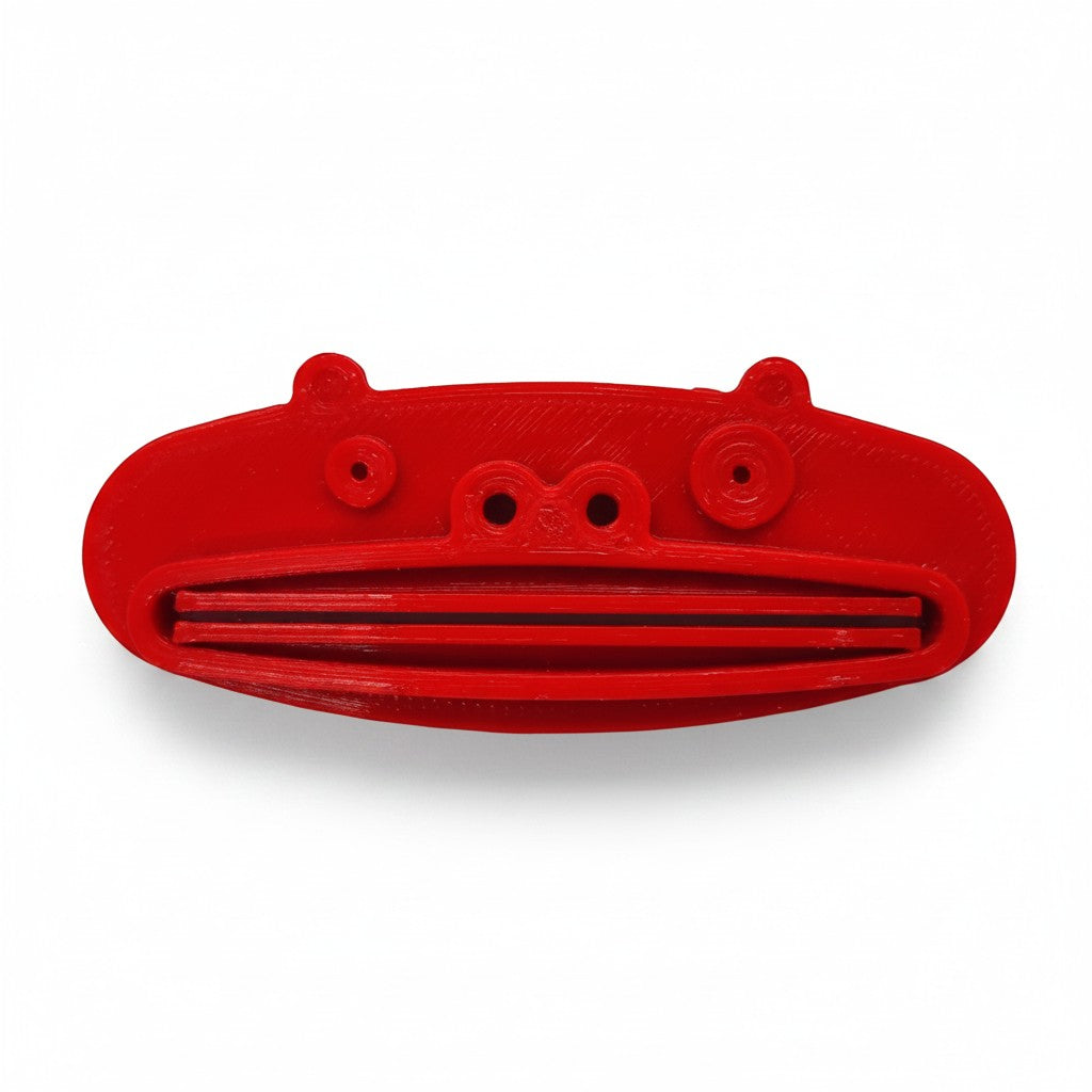 Magicland 3D red pig-shaped toothpaste squeezer with slots for dispensing.