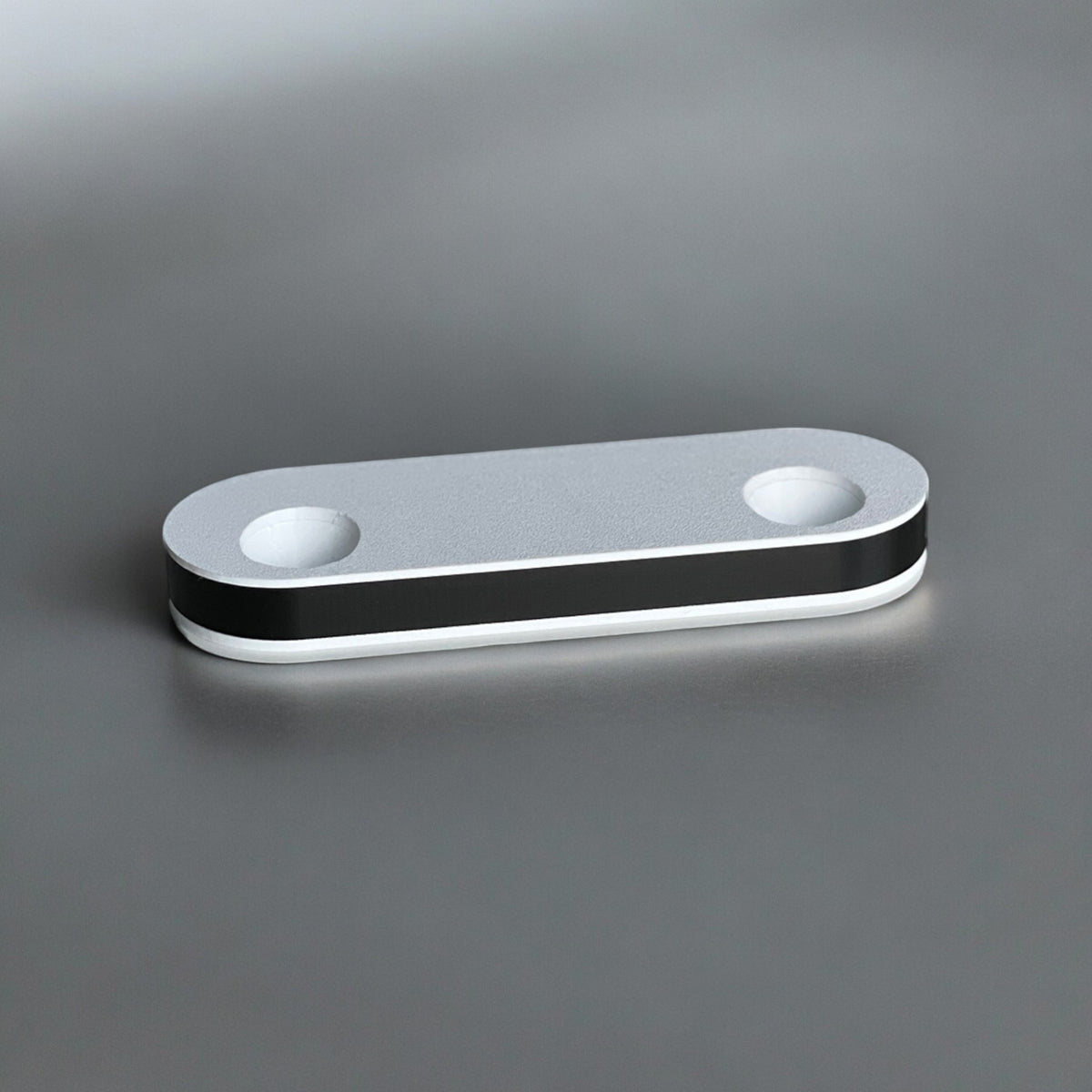 Magicland 3D minimalist silver phone stand with black and white trim, featuring two circular openings.