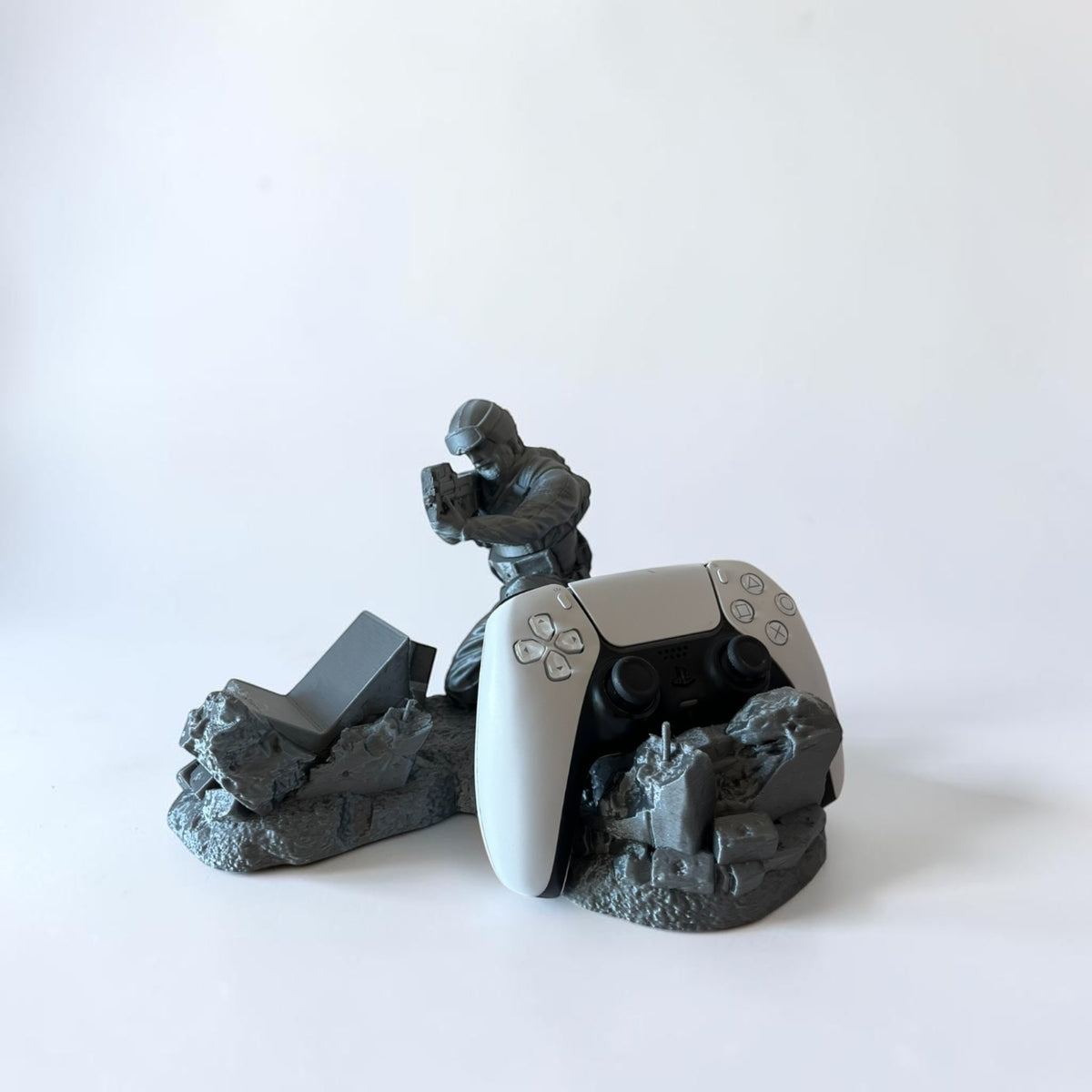 Magicland 3D soldier figure controller stand, grey, holding a weapon, with a white PS5 controller displayed.