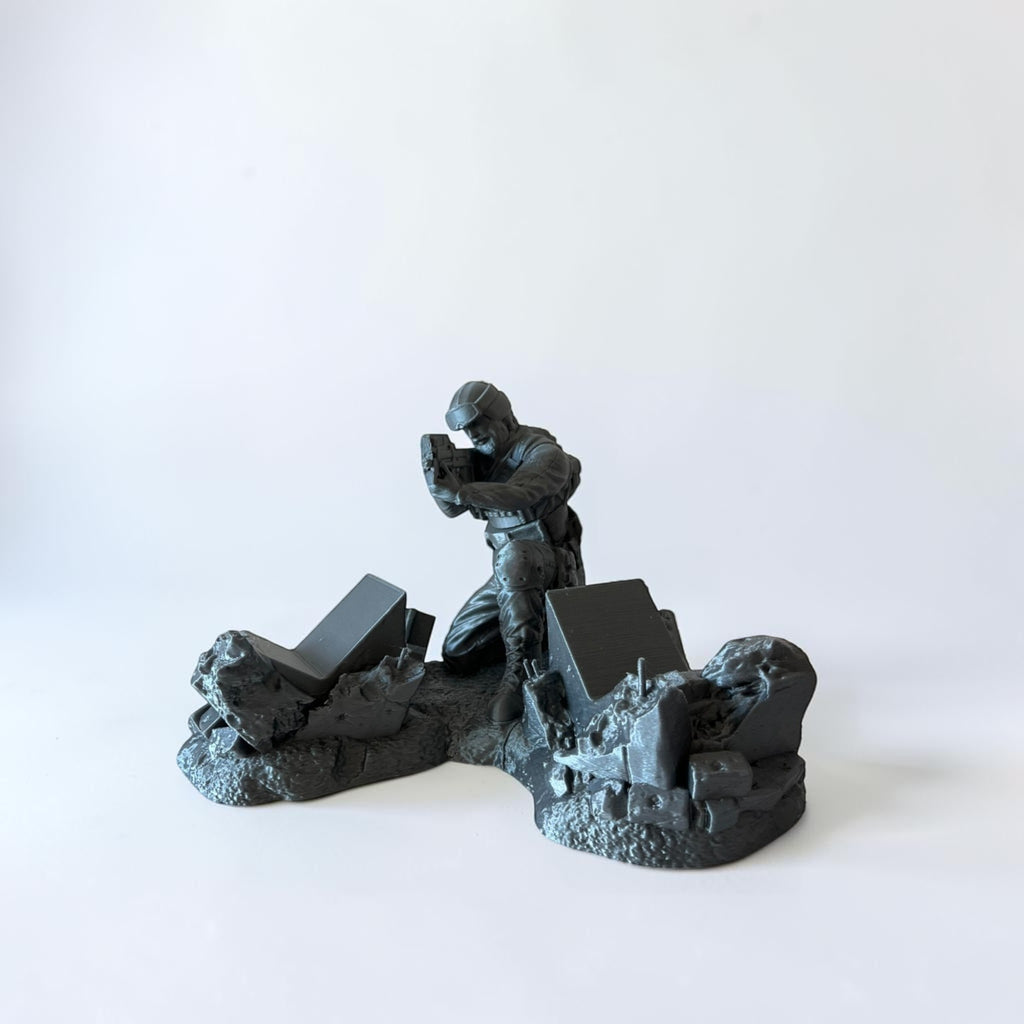 Magicland 3D grey resin figurine of a soldier aiming a weapon on a rubble base.